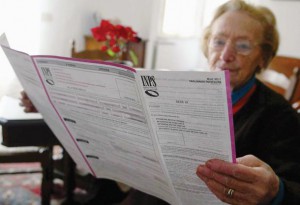 Un' anziana signora legge il modulo di richiesta per la pensione di vecchiaia.    ANSA - FRANCO SILVI -PAT