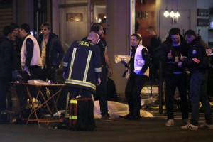 Police officers and rescue workers gather around a victim outside a Paris restaurant, Friday, Nov. 13, 2015. (ANSA/AP Photo/Thibault Camus)