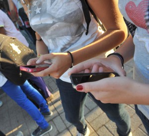 Due ragazze si scambiano messaggi sugli iPhone prima di entrare a scuola.ANSA/FRANCO SILVI