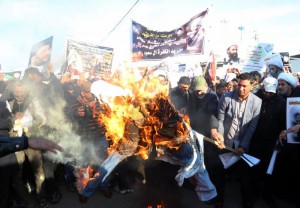 Followers of Shiite cleric Muqtada al-Sadr burn an effigy of King Salman of Saudi Arabia as they hold posters of Sheik Nimr al-Nimr and Shiite cleric Muqtada al-Sadr during a demonstration in Baghdad, Iraq, Monday, Jan. 4, 2016.  (ANSA/AP Photo/Khalid Mohammed)