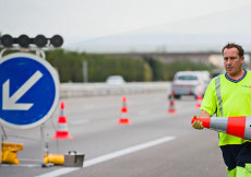 Addetti alla manutenzione autostradale rimuovono coni di segnalazione incidente.