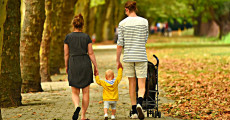 Padre, madre e bambino: una famiglia a spasso in un parco.