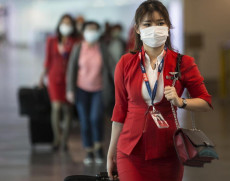 Hostess di AirAsia in transito all'aeroporto con la mascherina sul viso.