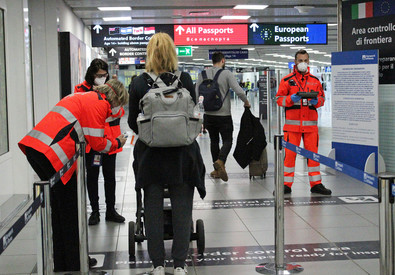 Personale di sicurezza con le mascherine controllano l'ingresso di viaggiatori all'aeroporto di Fiumicino