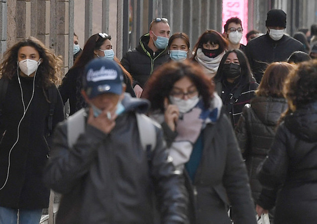 Persone con mascherina in una via di Milano.