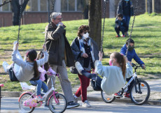 Persone camminano in un parco di Milano indossando mascherine, 24 marzo 2021.