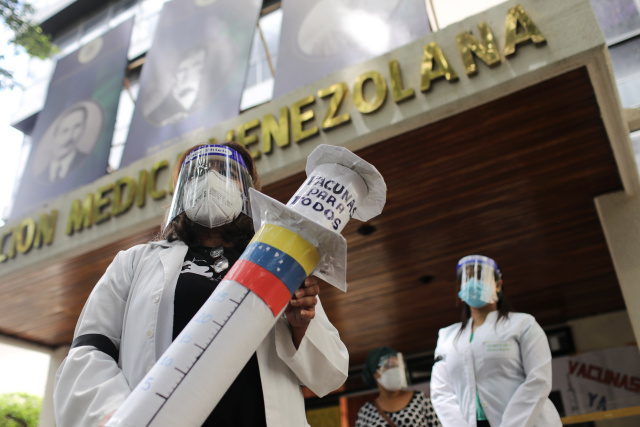 Un medico manifesta sostenendo una siringa gigante di carta durante una protesta della Federazione Medica Venezolana a Caracas.
