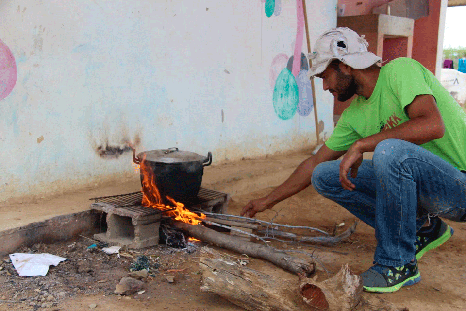 Un giovane accende un fuoco per cucinare in casa