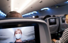 Hostess con la mascherina nello schermo del retrosedile di un aereo.