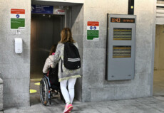 Accompagnatrice aiuta un disabile all'entrata della stazione.