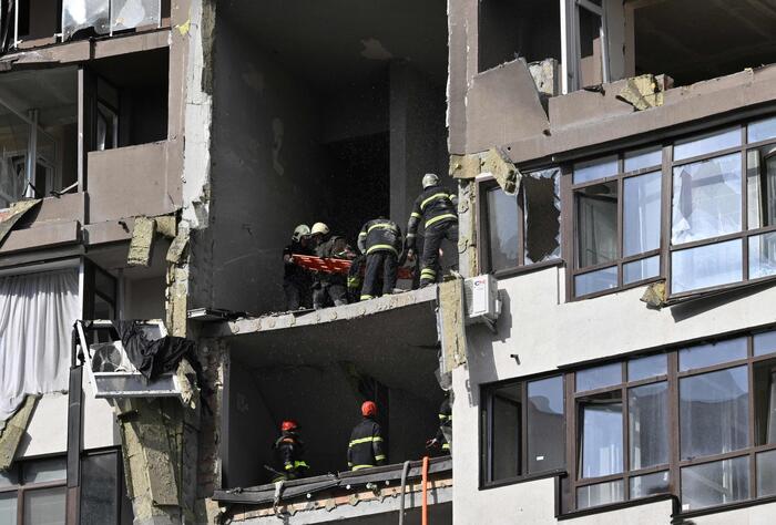 A Kiev i vigili del fuoco portano in salvo le persone da un edificio colpito dai missili russi.